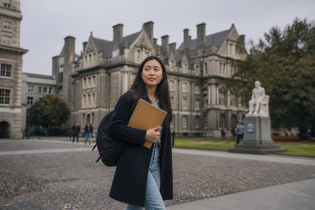 An international student crossing a university campus courtyard